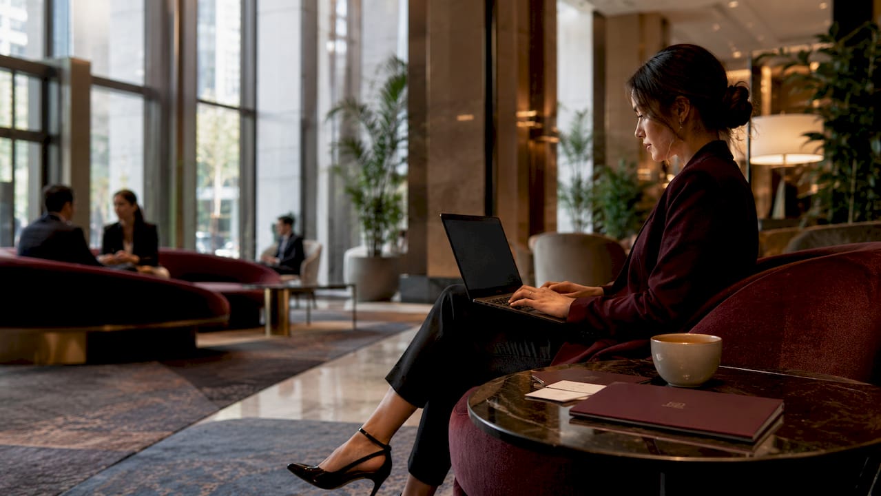 Woman using laptop in open hotel lobby seating area
