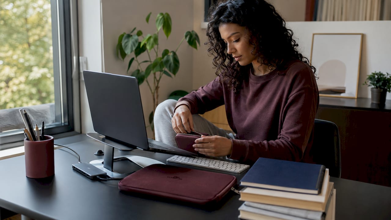 Student organizing MacBook study accessories at desk