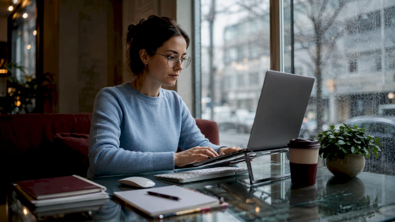 Woman adjusting MacBook ergonomic workspace setup