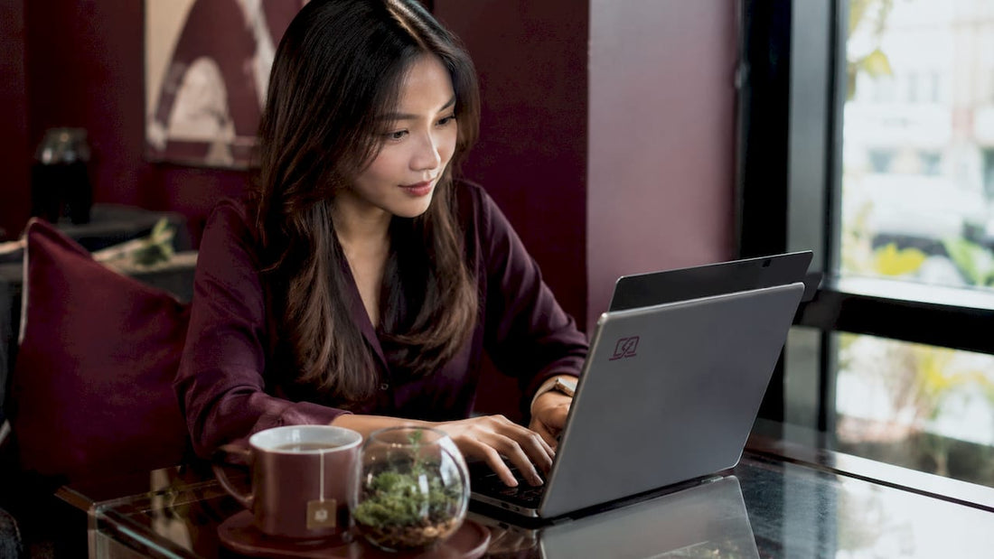 Young woman typing on MacBook with privacy screen