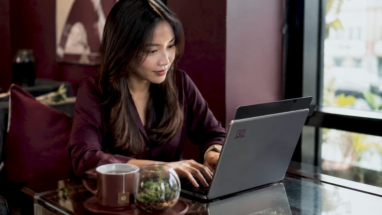 Young woman typing on MacBook with privacy screen