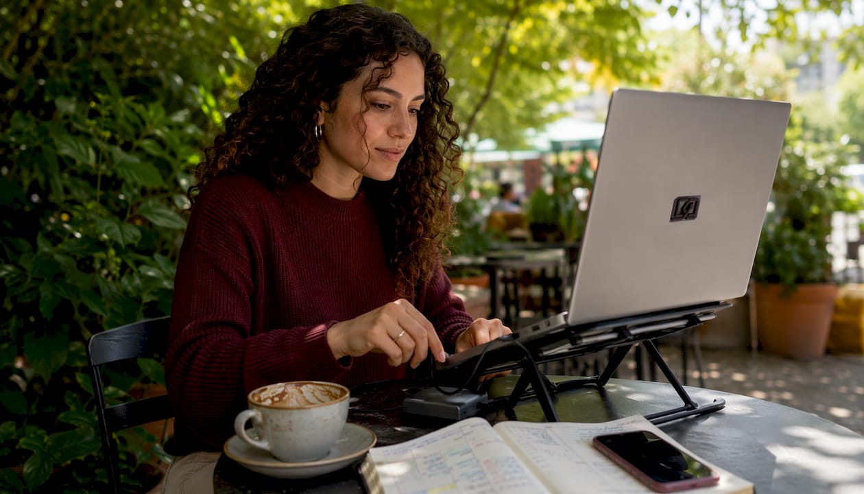 Person setting up laptop workspace in café