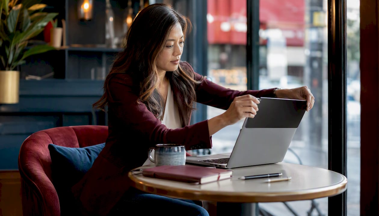 Woman attaching privacy screen to MacBook at hot desk