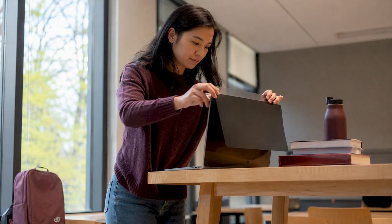 Person applying privacy filter on MacBook